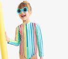 Child wearing Primary Long Sleeve One-Piece Rash Guard - Mist Rainbow Stripe. Available at www.tenlittle.com