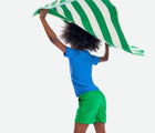 Child holding towel wearing Primary Swim Trunks in Green Apple - 2 Pack - Green Apple / Blueberry. Available at www.tenlittle.com