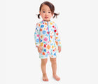 Child wearing Primary Baby One-Piece Rash Guard in Ivory Rainbow Block Print. Available from www.tenlittle.com