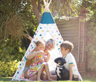 Children, mother, and dog playing in Bigjigs Teepee in the backyard. Available from www.tenlittle.com.