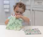 Child using Bumkins Large Reusable Snack Bag 2 pack in Llama & Cacti. Available at tenlittle.com
