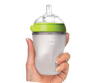 Woman's hand holding Comotomo 8oz baby bottle. Available from www.tenlittle.com