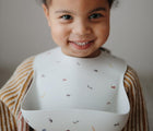 Baby Wearing Mushie Silicone Bib in Safari - Available at www.tenlittle.com