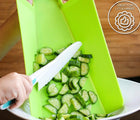 Child cutting cucumbers with tovla jr cutting board and knife. Available from www.tenlittle.com