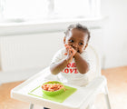 Baby in high chair with Ezpz Mini Bowl in lime. Available at www.tenlittle.com