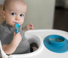 Baby in highchair using ezpz Tiny Spoon in blue. Available from tenlittle.com