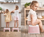 One view of two children each standing on BabyBjörn Step Stool in pink in the kitchen, and another view of child sitting on BabyBjörn Step Stool in pink in a playroom. Available from tenlittle.com