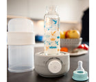Open view of Béaba 3-in-1 Bottle Warmer & Sterilizer with bottle inside, on a countertop. Available from tenlittle.com