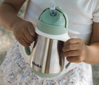 Child holding Beaba Stainless Steel Straw Sippy Cup. Available from tenlittle.com