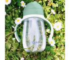 Beaba Straw Sippy Cup sitting in grass and flowers. Available from tenlittle.com