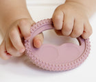 Child holding the mini development tool from ezpz Oral Development Tools in blush. Available from tenlittle.com