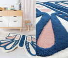 One view of Nico & Yeye Butterfly Rug in playroom next to dresser with Nico & Yeye Fuzzy Bunny Chair next to curtains, and one close up view of Nico & Yeye Butterfly Rug. Available from tenlittle.com