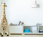 Nico & Yeye Cubbie Chest in a playroom next to 3 cubbies storage unit and a giant giraffe stuffed animal. Available from tenlittle.com