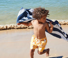 Boy using Dock & Bay Navy Blue Quick Dry Beach Towel on the beach
