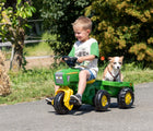 Boy riding in Kettler John Deere 3-wheeled pedal tractor with trailer with his dog. 