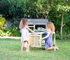 Two children playing with TP Toys Outdoor Mud Kitchen outside in the yard. Available from tenlittle.com