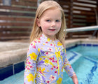 Child wearing Jan & Jul Long One Piece UV Swimsuit in Tropical Bloom in the pool. Available from tenlittle.com