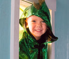 Child wearing Little Adventures Dragon Cloak costume looking through a window. Available from tenlittle.com