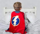 Child on bed wearing Little Adventures Hero Cape and Mask costume. Available from tenlittle.com