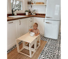 Boy sitting on Piccalio Convertible Kitchen Helper Tower in natural converted into table and eating food out of a bowl. Available from tenlittle.com