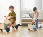 Girl and Boy riding Plan Toys Delivery Bike - Available at www.tenlittle.com