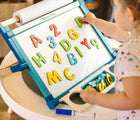 Child playing with Melissa & Doug Double-Sided Tabletop Easel. Available from tenlittle.com