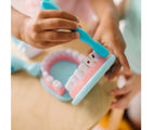 Child's hands brushing pretend teeth from Melissa & Doug Super Smile Dentist Play Set. Available from tenlittle.com