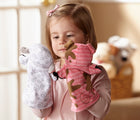 Child looking at sheep hand puppet in one hand and pig hand puppet in other hand from Melissa & Doug Farm Friends Hand Puppets. Available from tenlittle.com