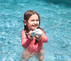 Girl playing with Sunnylife Shark Soaker in the pool.