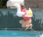 Child jumping in pool in Sunnylife Unicorn Float Ring. Available at www.tenlittle.com